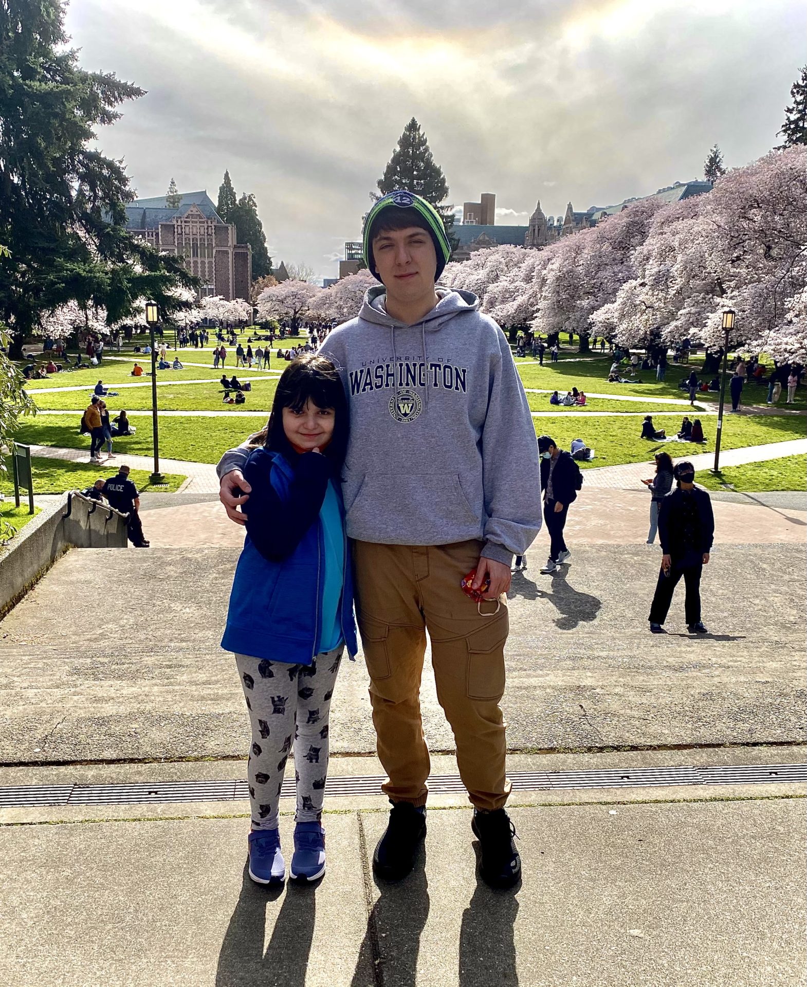 young man with younger sister in front of cherry blossom trees