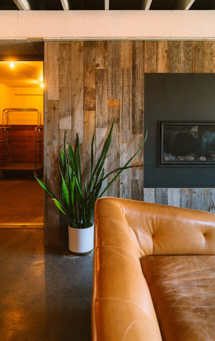 Cosy hotel lounge with leather sofa, rustic wood panelling, and modern fireplace, offering a warm, relaxing ambience.