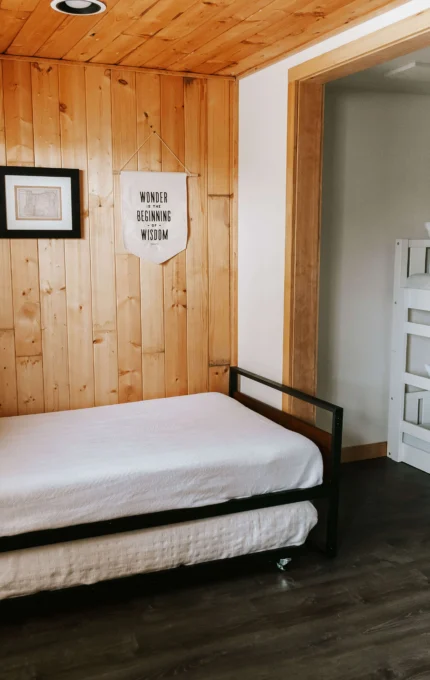 Cosy hotel room with wooden walls, comfy daybed, and modern bunk beds, ideal for families or groups seeking a warm retreat.