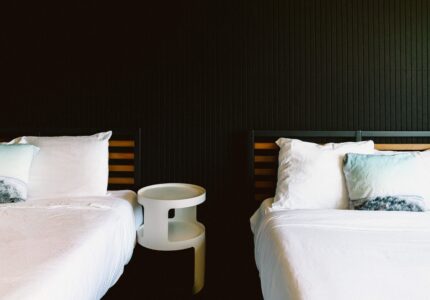 two queen beds with white linens and memory foam mattresses against a dark accent wall in a guest room at the Adrift Hotel in Long Beach, Washington.