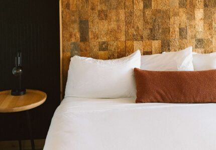 Close-up of a king bed with crisp white bedding and a cork headboard at the Adrift Hotel, a boutique beachfront hotel in Long Beach, Washington.