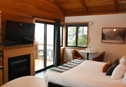 King room at the Inn at Manzanita, Oregon, with vaulted cedar ceilings, in-room fireplace, soaking tub, and a private deck among the trees.