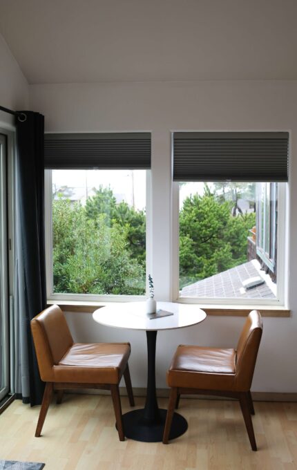 Corner bistro table for two with leather chairs and garden views in a Luxe King room at the Inn at Manzanita, Oregon