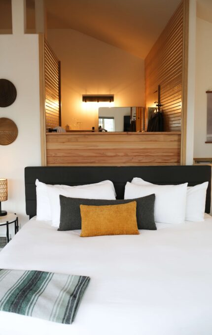 King bed with plush white bedding beneath a vaulted cedar loft wall in a Luxe King room at the Inn at Manzanita, Oregon