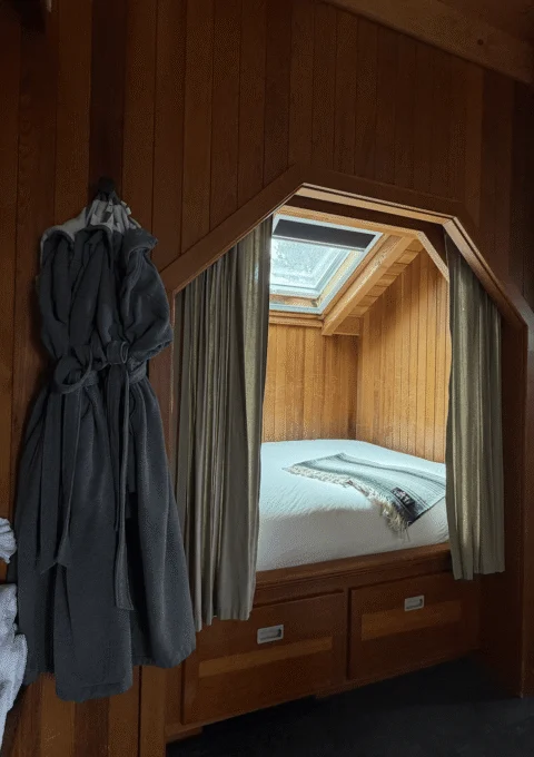 Cosy captain queen bed with a skylight, plush bedding, and soft robes, offering a serene and luxurious stay.