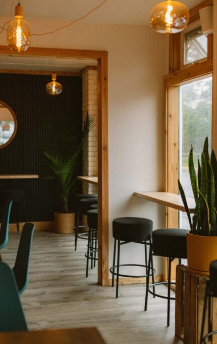 Stylish hotel lounge with modern decor, warm lighting, and cosy seating overlooking a scenic view.