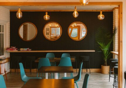 Stylish hotel lounge with modern decor, round mirrors, teal chairs, warm lighting, and games for guests to enjoy.