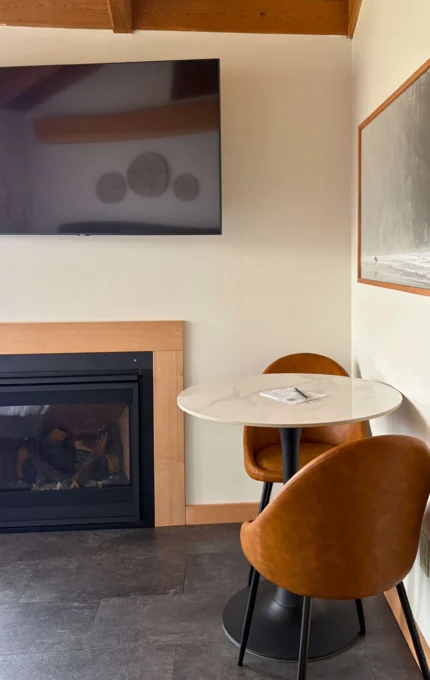 Cosy hotel room corner with TV, fireplace, and marble table perfect for relaxation. Experience comfort and style.