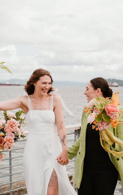 Two joyful women celebrating on a scenic waterfront deck adorned with vibrant flowers, perfect for romantic getaways or weddings.