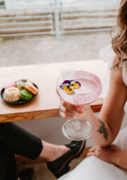 Guest enjoying vibrant cocktail with edible flowers in a stylish hotel lounge, macarons in the background.