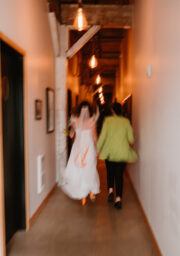 Guests walking down warmly-lit hotel corridor with rustic ceiling beams, creating a cosy atmosphere.