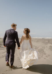 Romantic couple walking on sandy beach near luxury seaside hotel, perfect for beach weddings and coastal getaways.