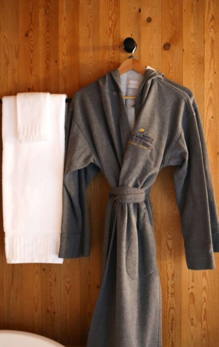 Cosy hotel room with bathrobe, soft towels, wooden accents, and stylish pendant lighting for a relaxing stay.