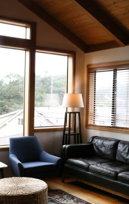 Cosy hotel lounge with large windows, leather sofa, blue chairs, and serene views promoting relaxation.