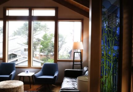 Cosy hotel lounge with comfy chairs, large windows, sea views, elegant stained glass, ideal for relaxing stays.