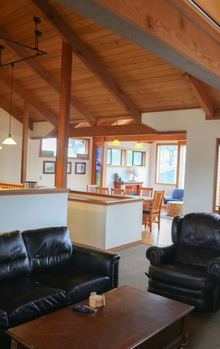 Spacious hotel lounge with leather sofas, wooden beams, and large windows offering natural light and mountain views.