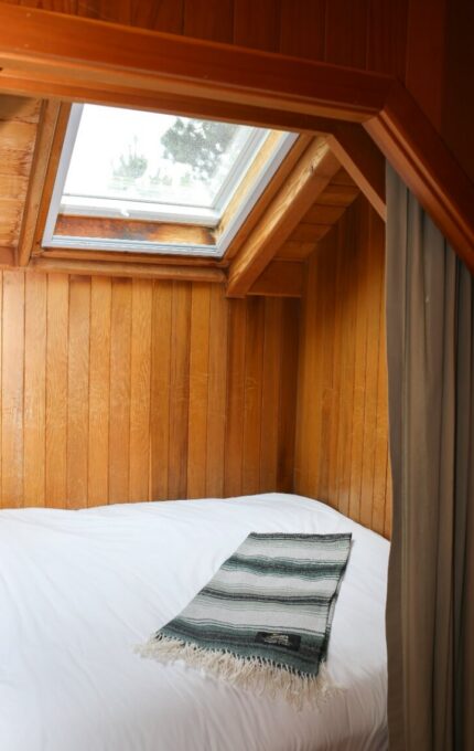 Cosy loft bedroom with skylight, white bedding, and warm wood panelling, perfect for serene relaxation.