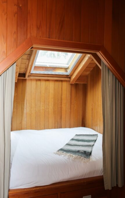 Cosy hotel room with skylight, wooden decor, and plush bedding invites relaxation and comfort.