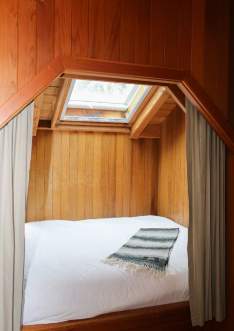 Cosy hotel room with skylight, wooden decor, and plush bedding invites relaxation and comfort.