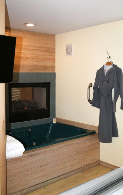 Luxurious hotel room with a cosy fireplace, relaxing whirlpool tub, and plush bathrobes for a serene, romantic retreat.