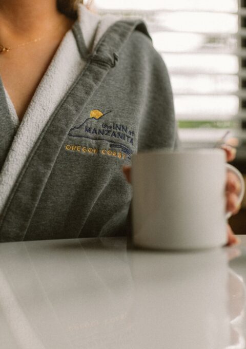 Guest enjoys coffee in cosy robe at seaside hotel with modern amenities.