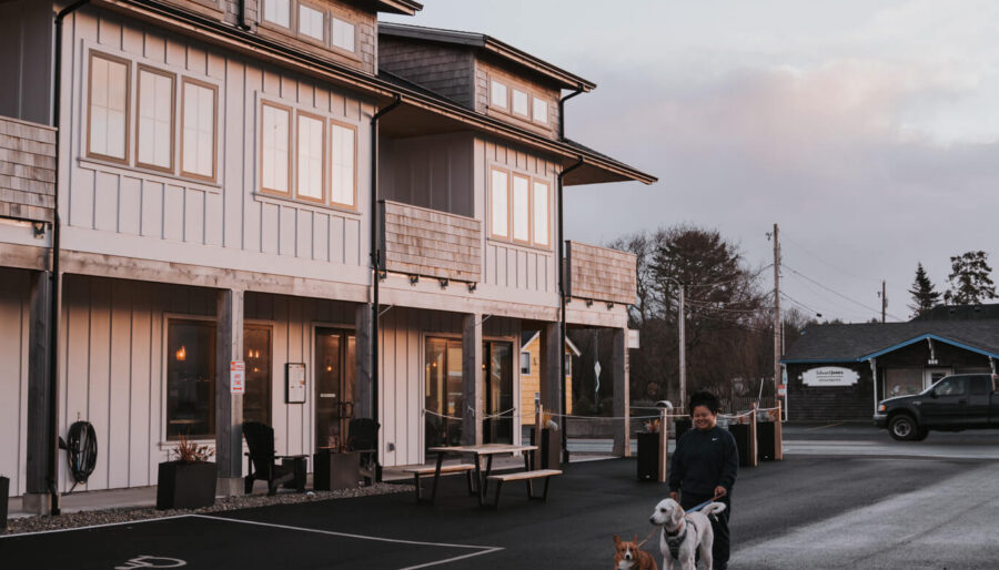 Guests walking their dogs at dusk outside Boardwalk Cottages, a pet-friendly place to stay in Long Beach, Washington