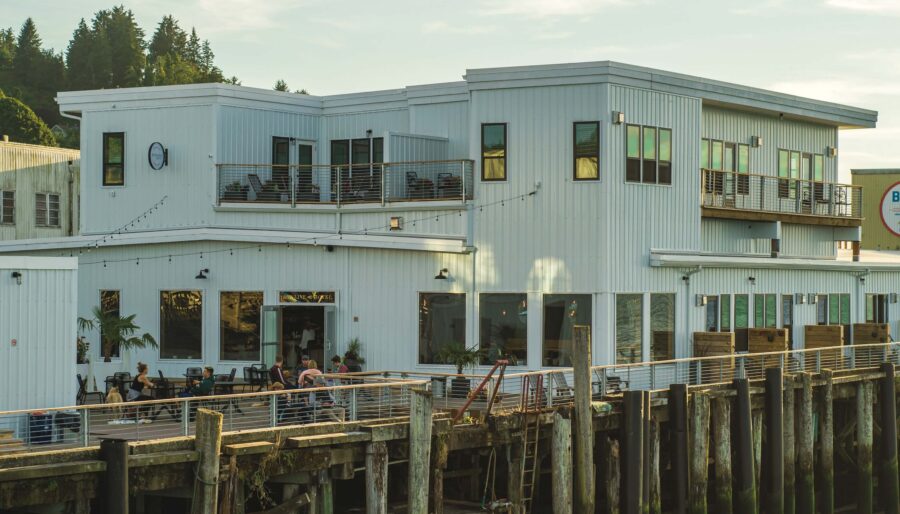 Guests dining on the pier deck at the Bowline Hotel in Astoria, Oregon, a waterfront boutique hotel built on historic cannery pilings