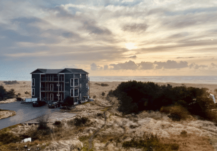 Coastal hotel surrounded by golden fields at sunset, offering serene ocean views and relaxing nature walks.