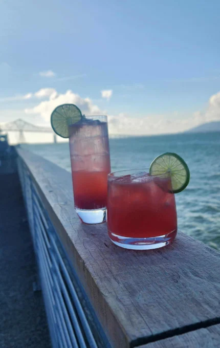 Two vibrant cocktails with lime by ocean view at luxury seaside hotel.